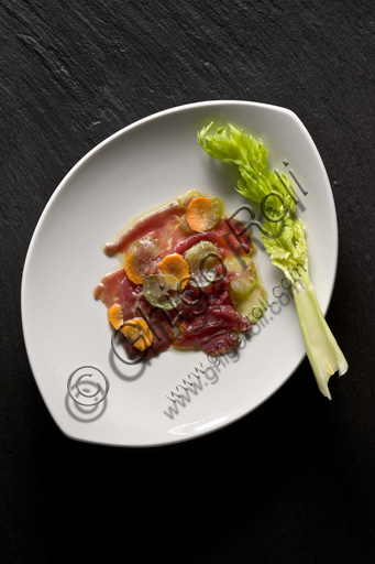  A plate of carpaccio (thinly sliced raw meat) decorated with carrots and celery.