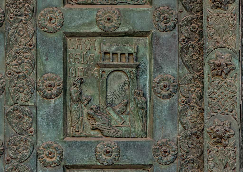 Duomo di Monreale, Porta di Bonanno Pisano (1185-6): formella bronzea con "La Resurrezione di Lazzaro" (scena dal Nuovo Testamento).La porta è firmata: "Bonanno civis pisanus". Iconograficamente nei cinque ordini inferiori vi sono scene del Vecchio Testamento, sette dedicate alla storia di Adamo ed Eva, e altre sei ad altrettante coppie di profeti mentre nei cinque superiori scene del Nuovo, al sommo Cristo e Maria nella gloria del Paradiso.