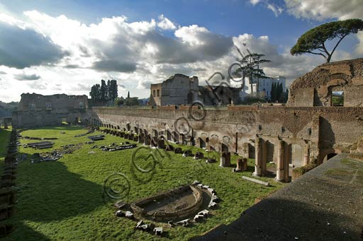 Roma, Palatino: Veduta dello Stadio Palatino (o ippodromo di Domiziano).Lo stadio è realizzato in mattoni i cui bolli laterizi sono tutti pertinenti alla fine del principato di Domiziano, con alcuni rifacimenti in epoca adrianea (nei portici) e severiana (nell'esedra). Il piccolo recinto ovale che si vede ancora oggi nella parte meridionale dell'arena risale infine all'epoca di Teodorico, quando forse venne usato come anfiteatro.Lo stadio doveva essere usato soprattutto come giardino e maneggio privato (Viridarium), come era d'uso nelle ville private dell'epoca.