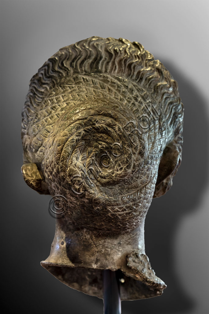 Brescia, "Santa Giulia, Museum of the City" (Unesco site since 2011):  portrait of a woman belonging to the Flavi family, bronze, lost wax casting, second half of the first century AD. The rich curly hair, often obtained with wigs, is typical of the women of the Flavi family. She could be Domizia Longina, wife of the Emperor Domitian, or Giulia, daughter of Emperor Titus. Rear part.It is one of the six Roman busts found in the ancient Capitolium in 1826.