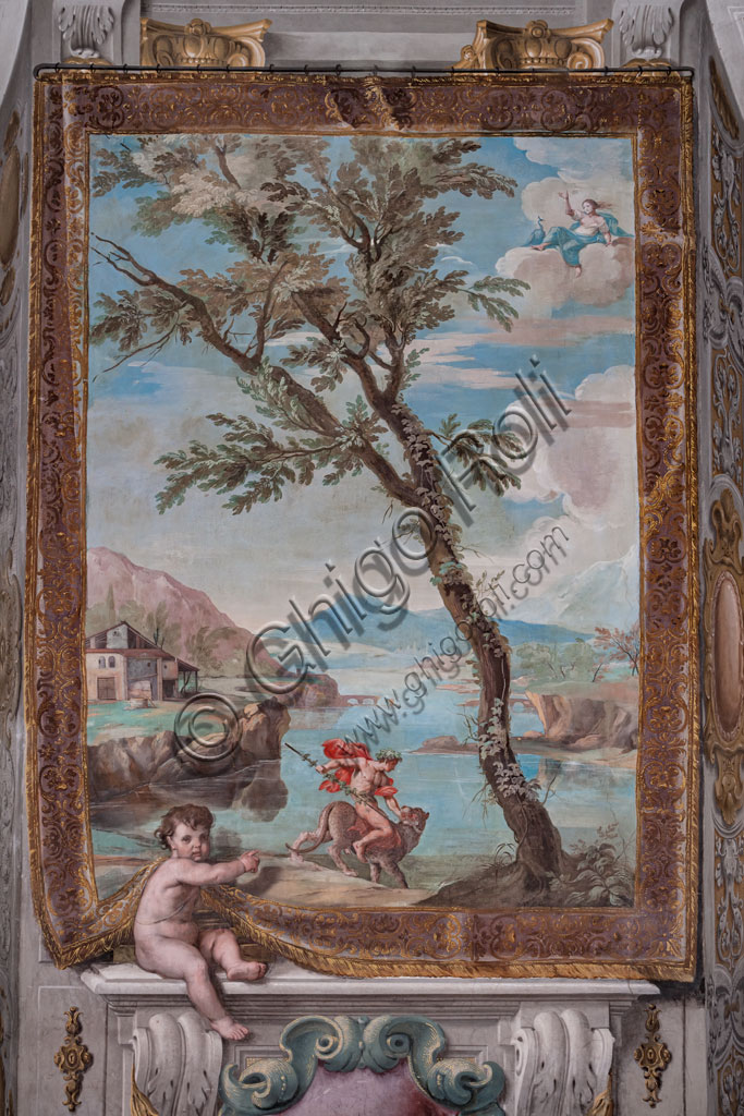 Sassuolo, Este Ducal Palace, the Bacchus Gallery: "Bacchus tames the tiger that the persecutor Juno sent against him". The faux tapestry depicting a river landscape dominated by a large tree in the centre, is raised by a putto on the left who indicates the scene. In the foreground Bacchus astride the tiger that Juno sent him.The goddess observes the scene from the clouds. It is one of the forty-one panels with scenes painted by Jean Boulanger which narrate the events of Bacchus. Wall tempera painting, 1650 - 52.