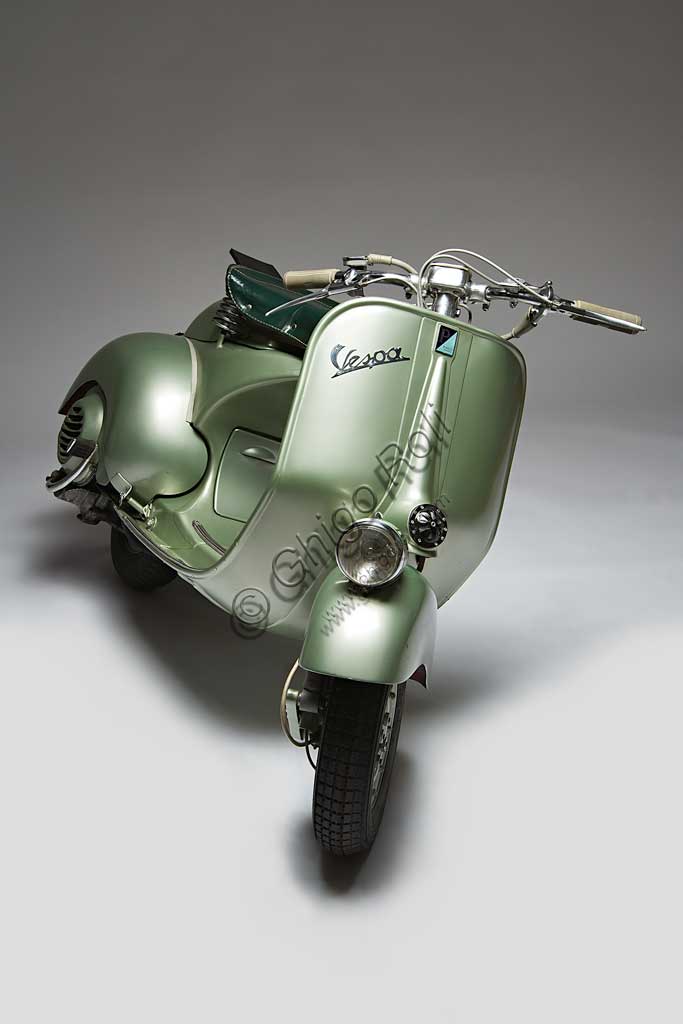 Moto d'epoca Vespa Sei Giorni. Scooter.Marca: Piaggiomodello: Vespa "Sei Giorni"nazione: Italia - Genova - Pontederaanno: 1951condizioni: restauratacilindrata: 124,2motore: monocilindrico a due tempicambio: al manubrio a tre rapportiLa Vespa, che apparve per la prima volta nel 1946, è in produzione ancor oggi ed è il motoveicolo più longevo della storia. Ne sono stati prodotti oltre 16 milioni di esemplari in 140 modelli. Venne concepita già durante la guerra e, dopo un primo prototipo denominato "Paperino", non particolarmente riuscito, Enrico Piaggio ne affidò il progetto a Corradino d'Ascanio, ingegnere aeronautico. Le soluzioni anticonformiste e geniali da lui adottate, oltre al grande bisogno di veicoli a basso costo che aveva l'Italia nel dopoguerra, ne decretarono un progressivo crescente successo, fino a farne, anche attraverso l'immagine che il cinema di quegli anni ne diffondeva, uno dei simboli dell'Italia. La "Sei Giorni" di queste pagine è uno dei modelli più rari.  Concepita per le corse, vinse nove medaglie d'oro all'olimpiade motociclistica del 1951, la "Sei Giorni Internazionale" di Varese.