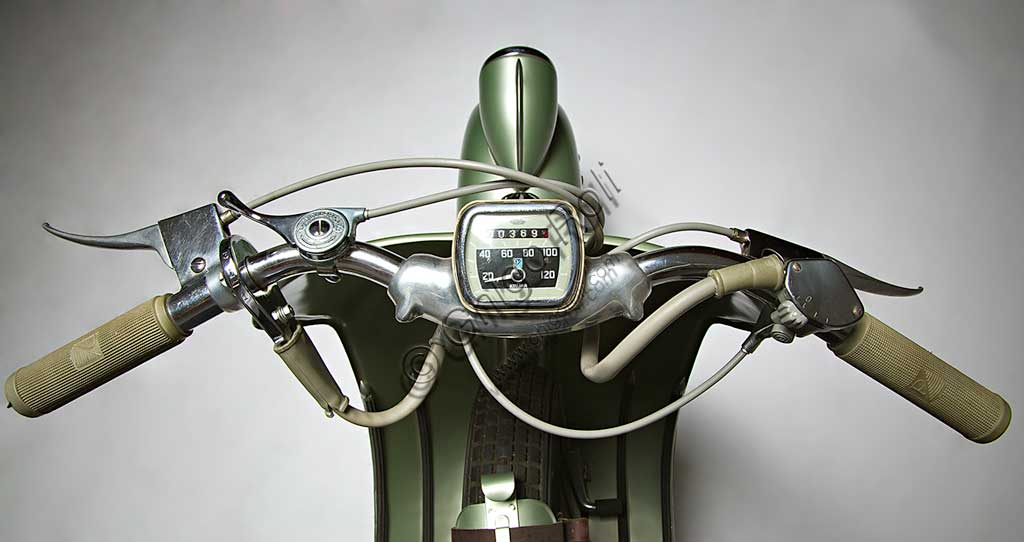 Moto d'epoca Vespa Sei Giorni. Scooter.Marca: Piaggiomodello: Vespa "Sei Giorni"nazione: Italia - Genova - Pontederaanno: 1951condizioni: restauratacilindrata: 124,2motore: monocilindrico a due tempicambio: al manubrio a tre rapportiLa Vespa, che apparve per la prima volta nel 1946, è in produzione ancor oggi ed è il motoveicolo più longevo della storia. Ne sono stati prodotti oltre 16 milioni di esemplari in 140 modelli. Venne concepita già durante la guerra e, dopo un primo prototipo denominato "Paperino", non particolarmente riuscito, Enrico Piaggio ne affidò il progetto a Corradino d'Ascanio, ingegnere aeronautico. Le soluzioni anticonformiste e geniali da lui adottate, oltre al grande bisogno di veicoli a basso costo che aveva l'Italia nel dopoguerra, ne decretarono un progressivo crescente successo, fino a farne, anche attraverso l'immagine che il cinema di quegli anni ne diffondeva, uno dei simboli dell'Italia. La "Sei Giorni" di queste pagine è uno dei modelli più rari.  Concepita per le corse, vinse nove medaglie d'oro all'olimpiade motociclistica del 1951, la "Sei Giorni Internazionale" di Varese.