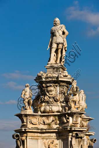 Palermo, the Parliament Square: The Marble Theatre, monument to Philip V, facing The royal Palace or Palace of the Normans. It was realised by Gaspare Guercio, Carlo D'Aprile and Gaspare Serpotta to celebrate the glory of Philip IV of Habsburg, king of Spain and Sicily, called Philip the Great.Around the pedestal  the four parts of the Earth known at that time (Europe, Asia, Africa and America), on which the king of Spain ruled, are depicted. On the first level there are the statues of the four Moors, or the previous kings of the countries that went under his domination. The work is adorned with plaques and coats of arms of the most important families in Sicily. The original statue of Philip IV was destroyed during the Sicilian revolution in 1848 and was replaced in 1856 by the current marble statue representing King Philip V of Spain and was realised by Nunzio Morello.