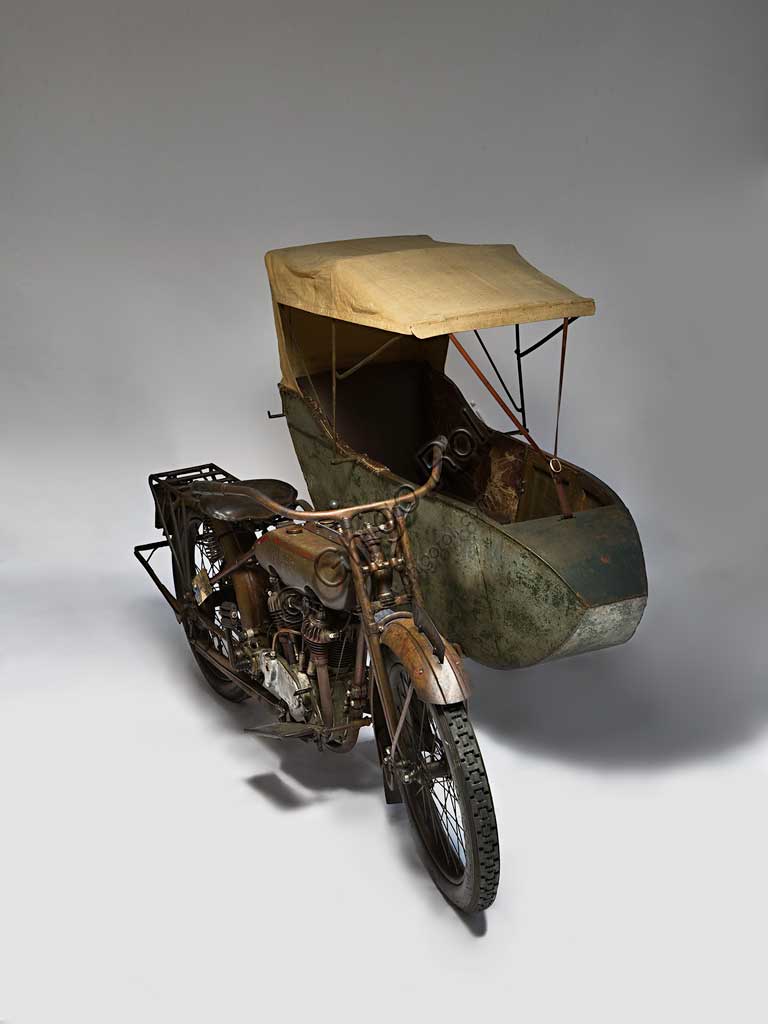 Moto d'epoca Harley-Davidson T - SideMarca: Harley-Davidsonmodello: T Sidenazione: U.S.A. - Milwaukeeanno: 1917condizioni: conservatacilindrata: 1000 (alesaggio e corsa 84,1 x 88,9)motore: bicilindrico a V di 45°cambio: a tre rapportiFondata nel 1903 la H-D ha accompagnato tutta la storia degli Stati Uniti fino ad oggi, dalle prime moto militari usate nelle schermaglie di confine contro Pancho Villa, alle grandi forniture per l'esercito che nel 1917 era entrato in guerra sul fronte europeo, dai mezzi da lavoro (i "tricicli" dei lattai e dei postini americani) alle grandi bicilindriche della polizia.. Già nel '20 era il primo produttore di motociclette al mondo.Questo elegante sidecar del 1917, integralmente conservato e perfettamente funzionante, mostra già il bicilindrico a V che caratterizza ancor oggi la produzione della Harley. Ha distribuzione a valvole contrapposte (scarico laterale, aspirazione in testa).