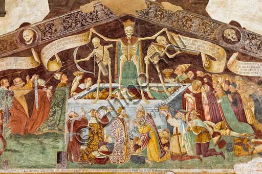  Clusone, Oratory of Disciplini or St. Bernardino, façade: frescoes with the Triumph of Death on the top and a Dance of Death (Macabre Dance) in the lower register (1485). All the frescoes are by Giacomo Borlone De Buschis.Detail of the Triumph of Death standing on a sarcophagus where the dead Pope and the Emperor lie. Theay are surrounded by serpents, scorpions and toads (symbols of pride and sudden death). Death hold big scrolls to remind everyone that Life is not everlasting.