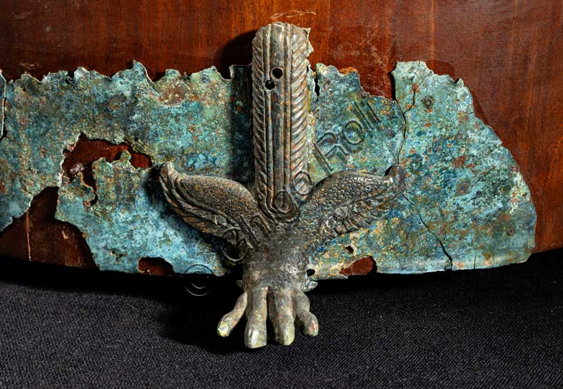 Museo Civico Archeologico di Bologna: corredo funerario dalla tomba 103 della necropoli De Luca.Al centro è la cista in bronzo inventario 16537. La cista era originariamente costituita da un corpo di legno rivestito di cuoio, non conservato in originale ma ricostruito, sul quale era montata una lamina traforata di bronzo.Il contenitore è decorato con elementi di bronzo: i piedi sono a forma di zampe di leone, a metà dell'altezza del corpo sono inserite delle piccole teste di ariete e sul coperchio la presa è costituita da una piccola e graziosa figura di atleta che esegue il ponte.Nella cista la donna etrusca riponeva i propri oggetti da toilette: l'alàbastron, cioè il contenitore per olii profumati, il pettine in osso e lo specchio di bronzo, le pinzette e gli altri materiali per la cura del corpo.Metà del V secolo a.C. Inv. 16537.Particolare di uno dei piedi a forma di zampa di leone.