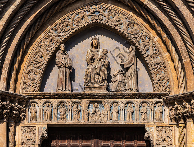 Vicenza, Chiesa di San Lorenzo, facciata, il portale: nella lunetta “ Madonna in trono con Bambino, San Francesco e S. Lorenzo che le presenta un nano” (Pietro da Marano, consigliere degli Scaligeri e committente), nell’architrave “Padre Eterno e otto Santi”. Opera di Andriolo de’ Santi e aiuti, 1342-4.